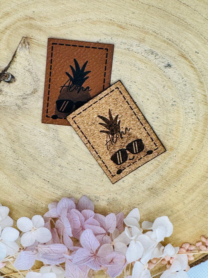 superweiches Kunstlederlabel mit einer coolen Ananas und dem Spruch Aloha in zwei Farben abgebildet