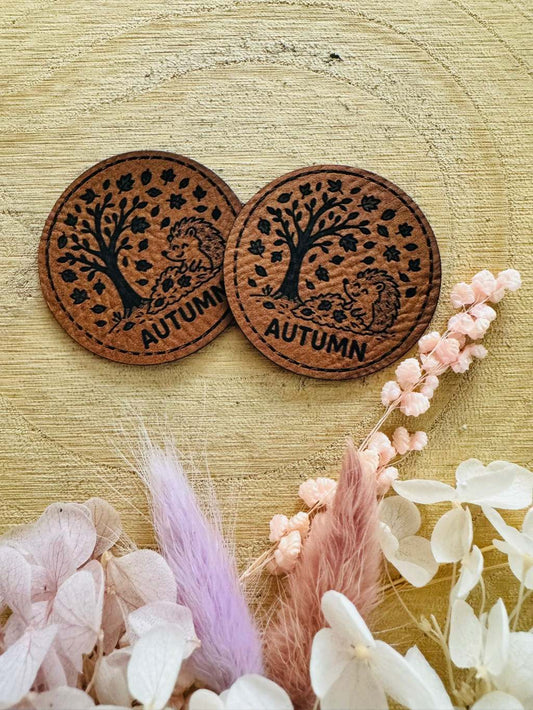 superweiches rundes braunes Kunstlederlabel mit dem Spruch Autumn und einem kleinen Igel im Herbstwind abgebildet
