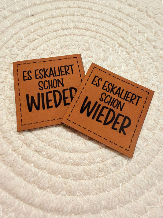 superweiches braunes Kunstlederlabel mit dem Spruch Es eskaliert schon wieder