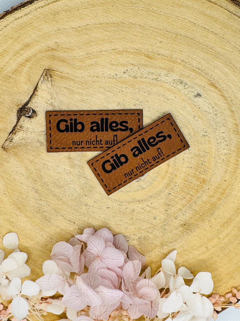 superweiches braunes Kunstlederlabel mit dem Spruch Gib alles komma nur nicht auf 