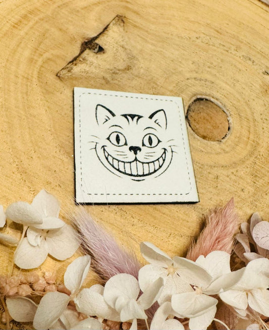 superweiches beiges im Dunkeln leuchtendes Kunstlederlabel mit einer frechen Katze abgebildet