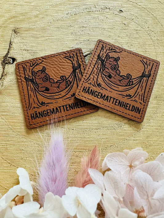 superweiches braunes Kunstlederlabel mit dem Spruch HängemattenHeldin und einem kleinen in einer Hängematte liegenden Schäfchen