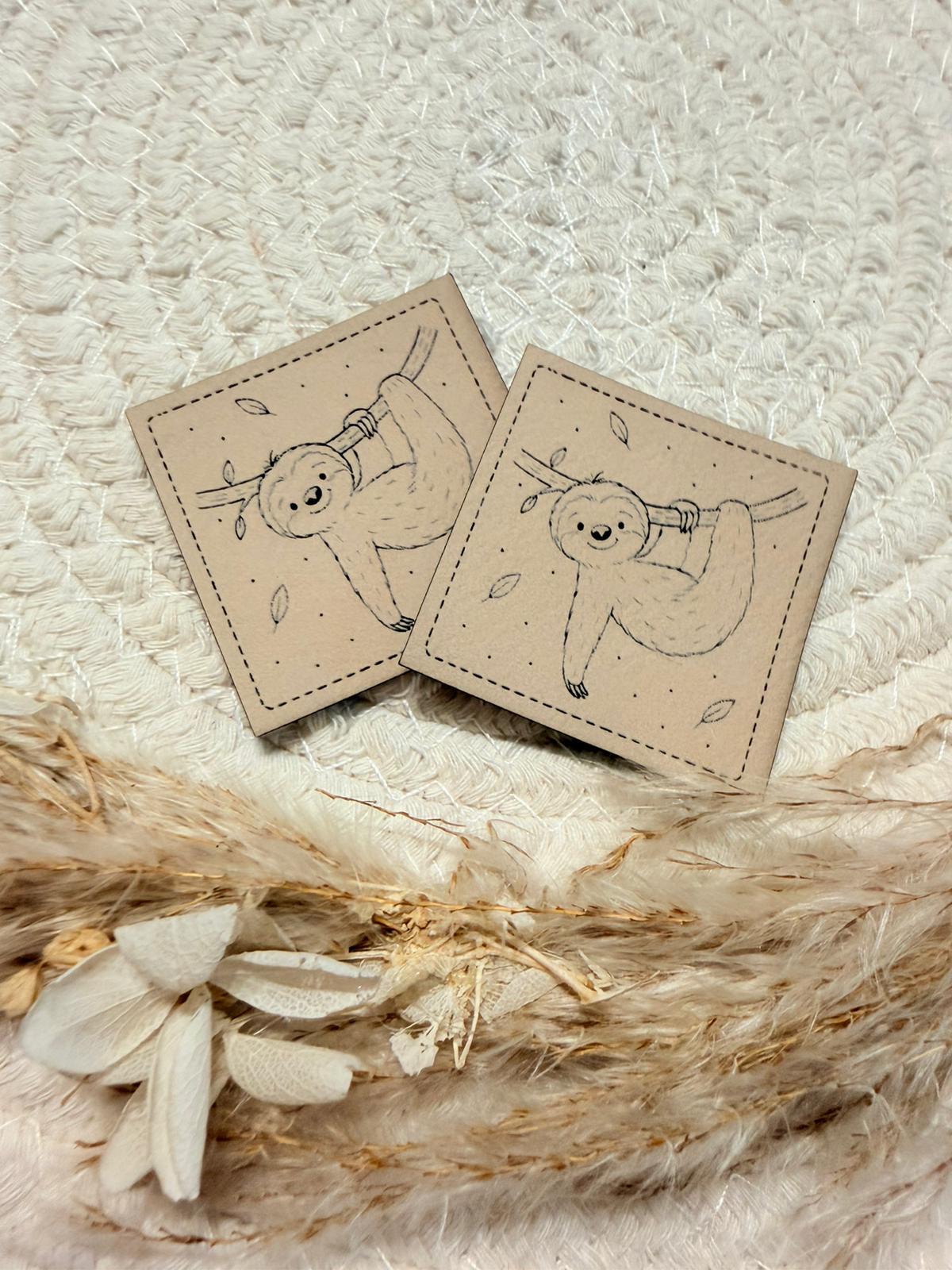 superweiches beiges Kunstlederlabel mit einem kleinen lustigen an einem Ast hängenden Faultier