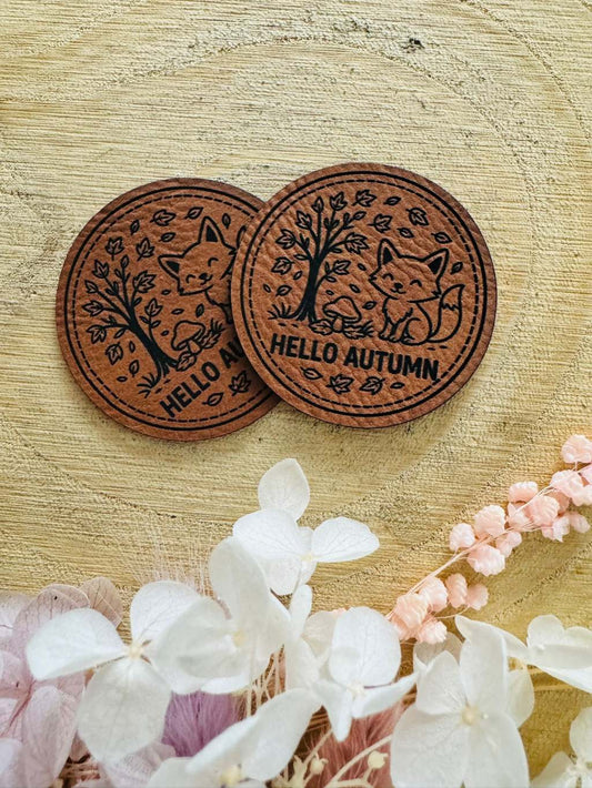 superweiches rundes braunes Kunstlederlabel mit dem Spruch Hello Autumn und einem kleinen Fuchs im Herbstwald abgebildet