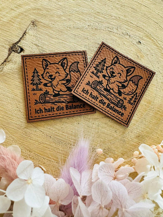 superweiches braunes Kunstleder Label mit einem auf einem Stamm balancierendem kleinen Fuchs und dem Spruch Ich halt die Balance
