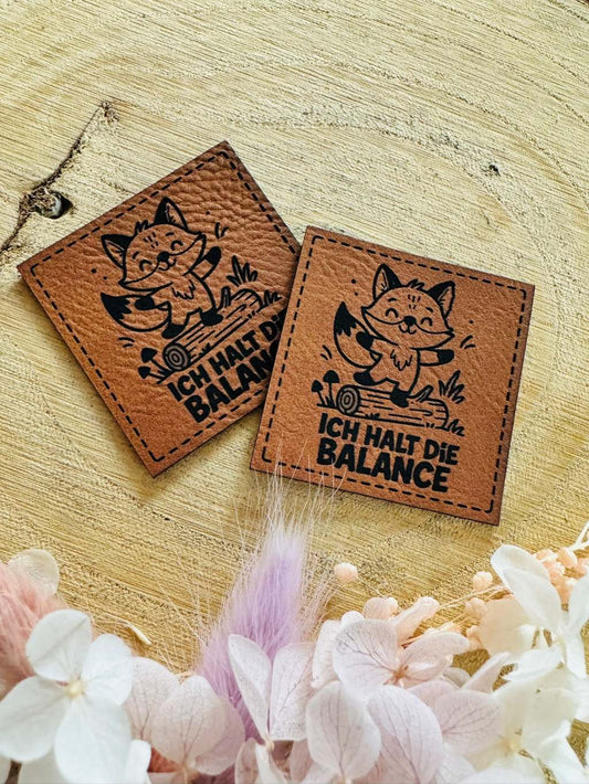 superweiches braunes Kunstleder Label mit einem auf einem Baum balancierenden kleinen Fuchs und dem Spruch Ich halt die Balance