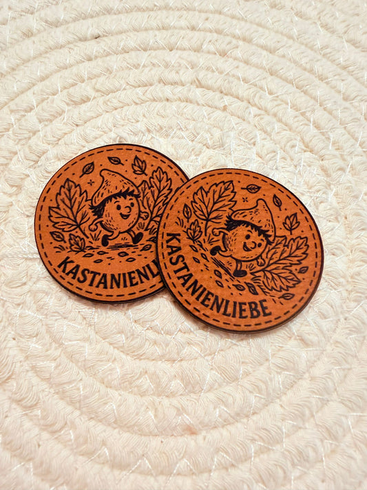 superweiches braunes rundes Kunstlederlabel mit dem Spruch Kastanienliebe und einer kleinen im Herbstwald laufenden Kastanie
