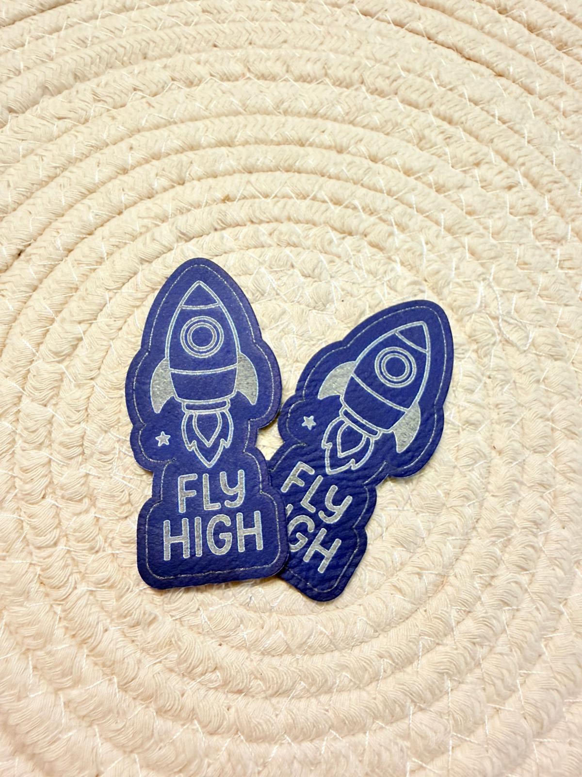 superweiches blaues Kontur Kunstlederlabel mit einer startenden Rakete und dem Spruch Fly High