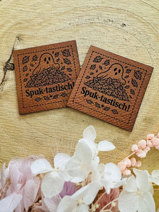 superweiches braunes Kunstleder-Label mit dem Spruch Spuk-tastisch und einem kleinen Gespenst in einem Blätterhaufen versteckt