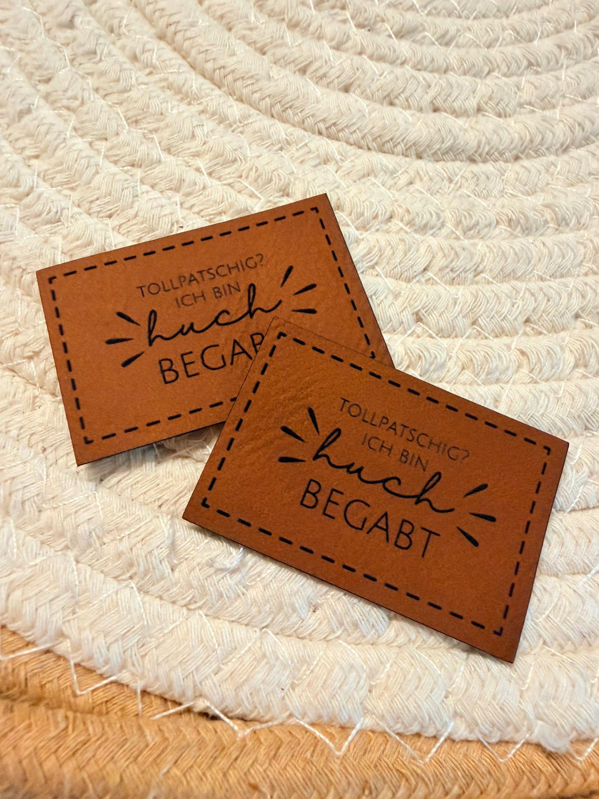 superweiches braunes Kunstlederlabel mit dem Spruch Tollpatschig? Ich bin huch begabt