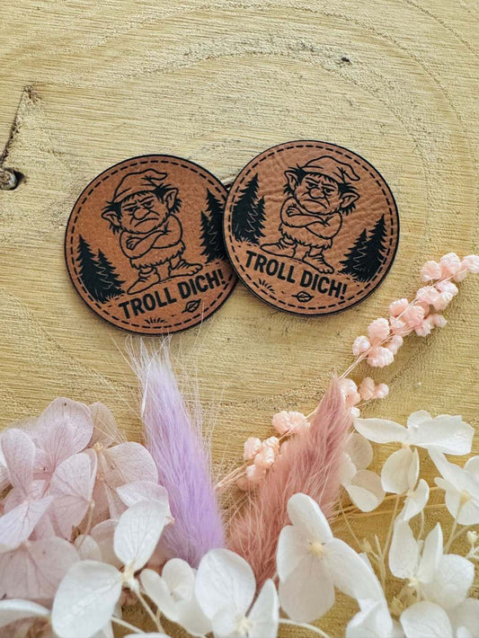 superweiches undes braunes Kunstlederlabel mit dem Spruch Troll Dich! und einem griesgrämig dreinschauenden Troll abgebildet