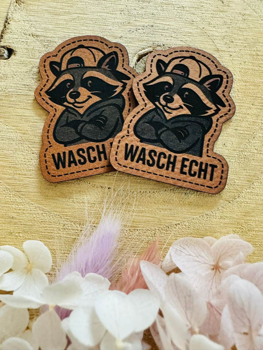 superweiches braunes Kontur Kunstleder Label mit einem kleinen pfiffigen Waschbär und dem Spruch Wasch Echt abgebildet