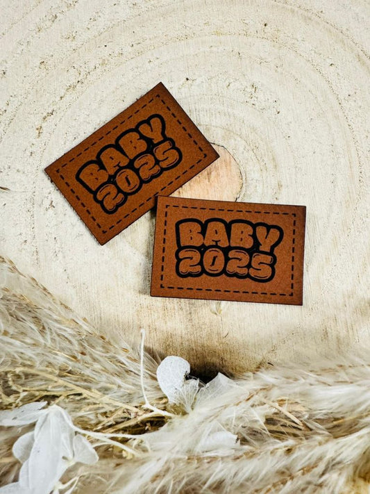 superweiches braunes Kunstlederlabel mit dem Spruch Baby2025 in schwarzer Schrift