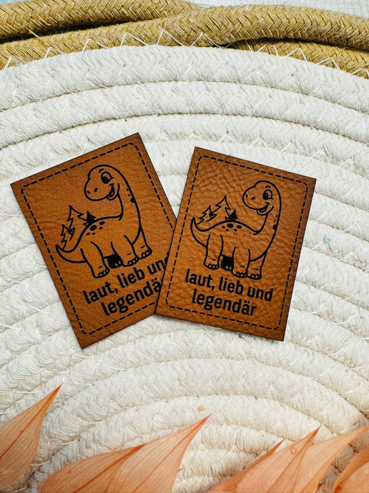 superweiches neues braunes Kunstlederlabel von den Bienenkindern mit dem Spruch laut lieb und legendär mit einem kleinen Dino abgebildet
