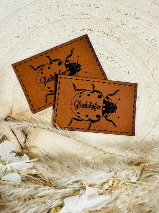 superweiches braunes Kunstlederlabel mit einem Glückskäfer abgebildet