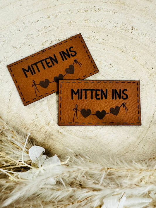 superweiches braunes Kunstlederlabel mit dem Spruch Mitten ins und drei kleinen Herzchen an einer Schnur befestigt