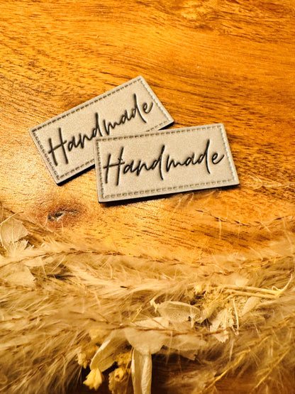 silber graues reflektierendes Kunstlederlabel mit dem Spruch Handmade