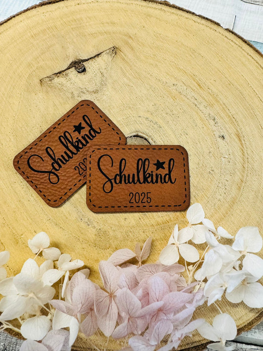 superweiches braunes Kunstlederlabel mit dem Spruch Schulkind 2025 und einem kleinen Stern