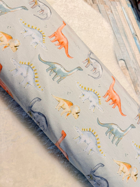 schöner Jersey Stoffmit Motiv Dino Parade auf beigem Untergrund