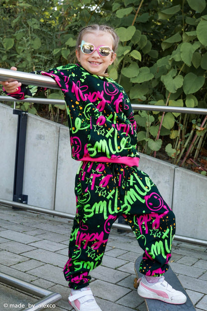 toller Kuschelsweat Stoff mit dem Motiv Happy Smile in Neonfarben auf schwarzem Untergrund - Beispielbild
