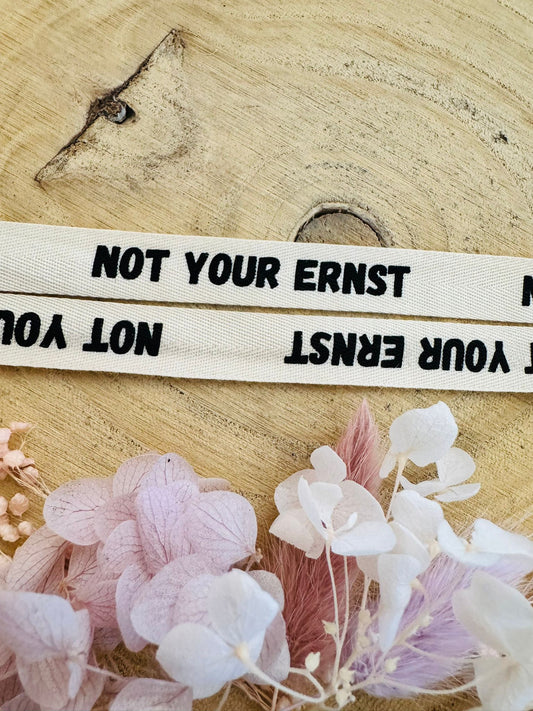 schönes weisses Baumwoll Webband mit dem durchgehenden Spruch Not Your Ernst in schwarzer Schrift