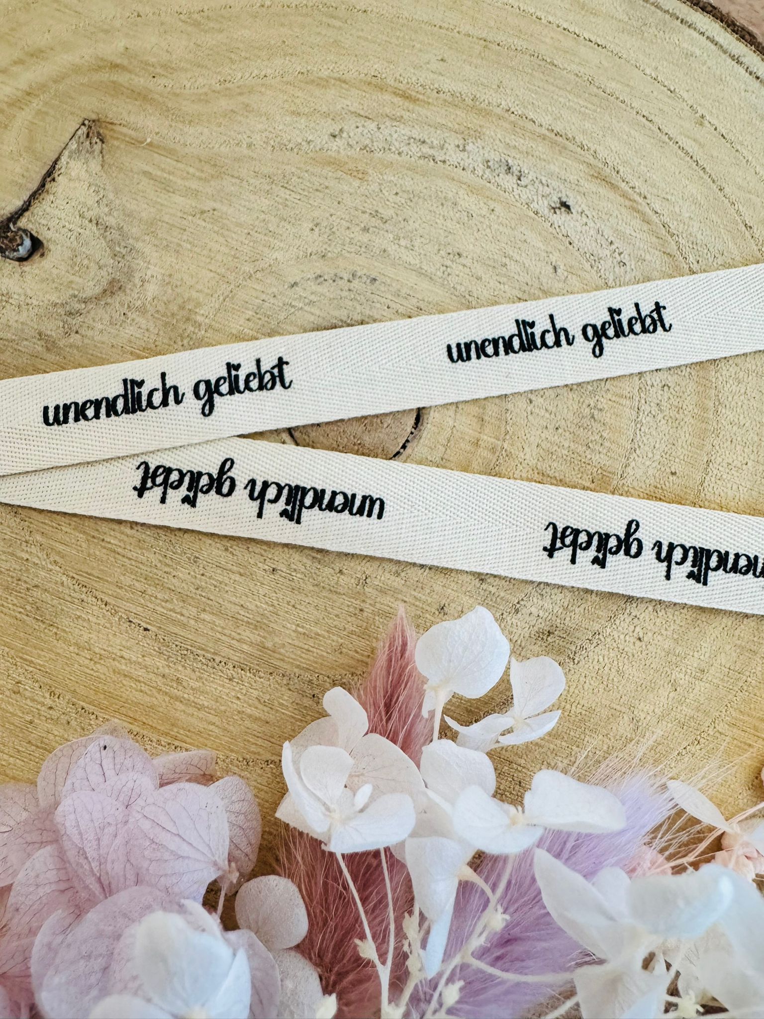 schönes weisses Baumwoll Webband mit dem durchgehenden Spruch unendlich geliebt in schwarzer Schrift