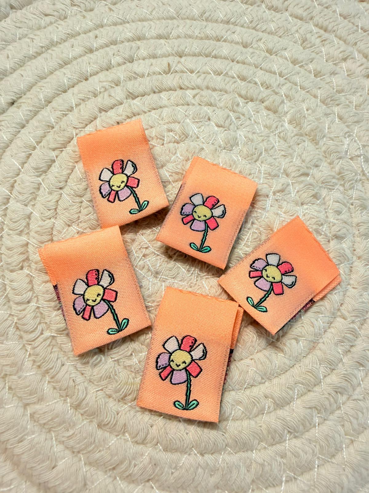 tolles Klapp Weblabel mit einem kleinen bunten Gänseblümchen auf orangenem Untergrund