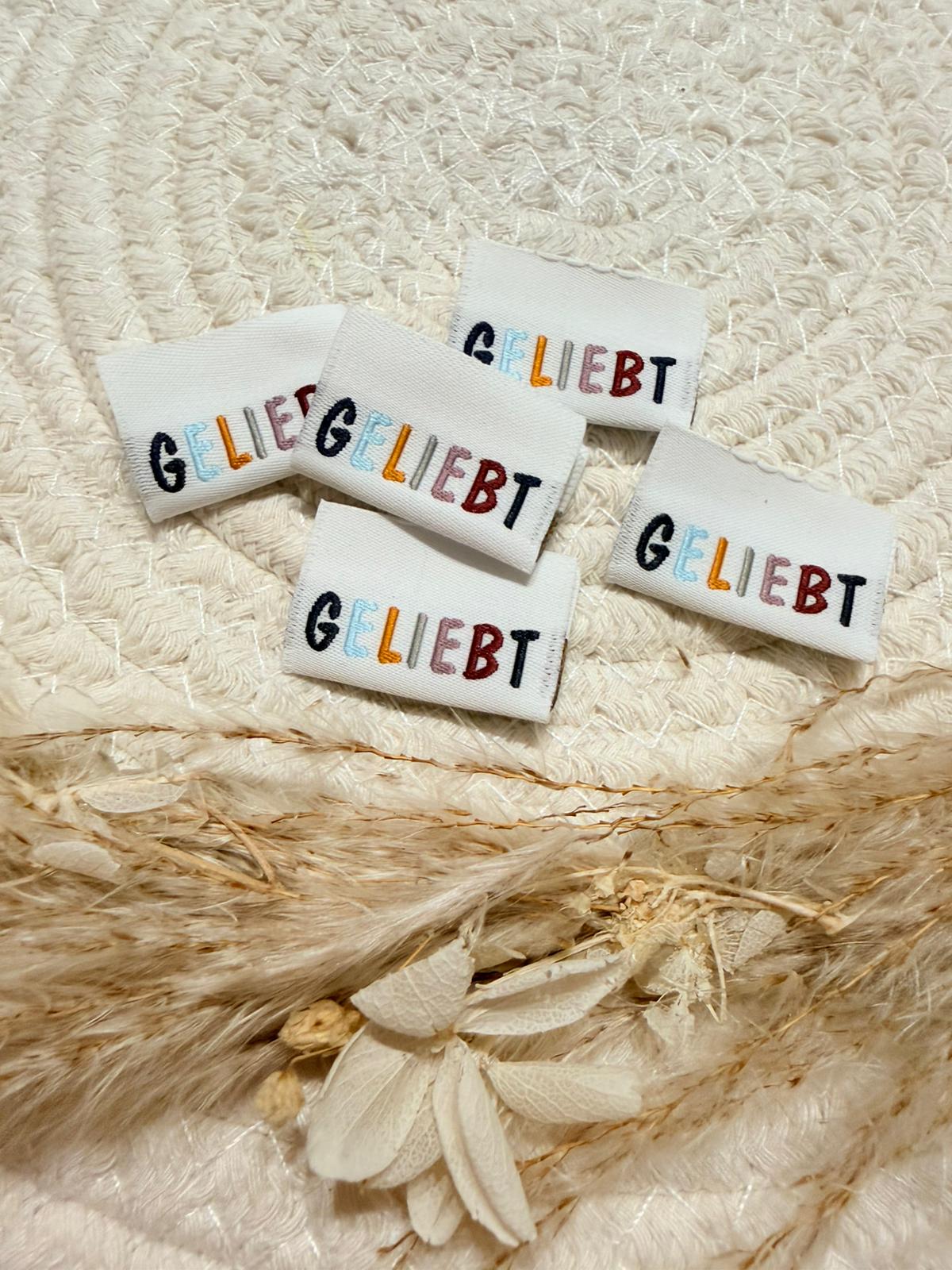 tolles weisses Weblabel mit dem Spruch Geliebt in bunten Buchstaben