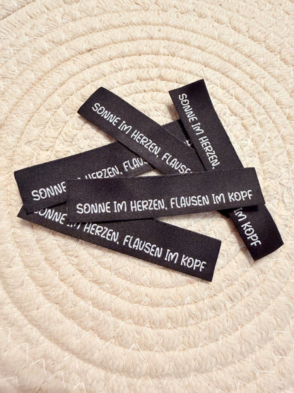 tolles neues Klapp Weblabel der Bienenkinder zum Einnähen mit dem Spruch "Sonne im Herzen, Flausen im Kopf" in schwarzer Ausführung